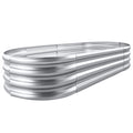 Large oval galvanized metal raised garden bed kit assembled outdoors with soil and vegetables
