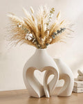 Two white ceramic heart-shaped vases on a table