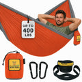 Orange and grey Wise Owl Outfitters parachute nylon camping hammock hung between trees