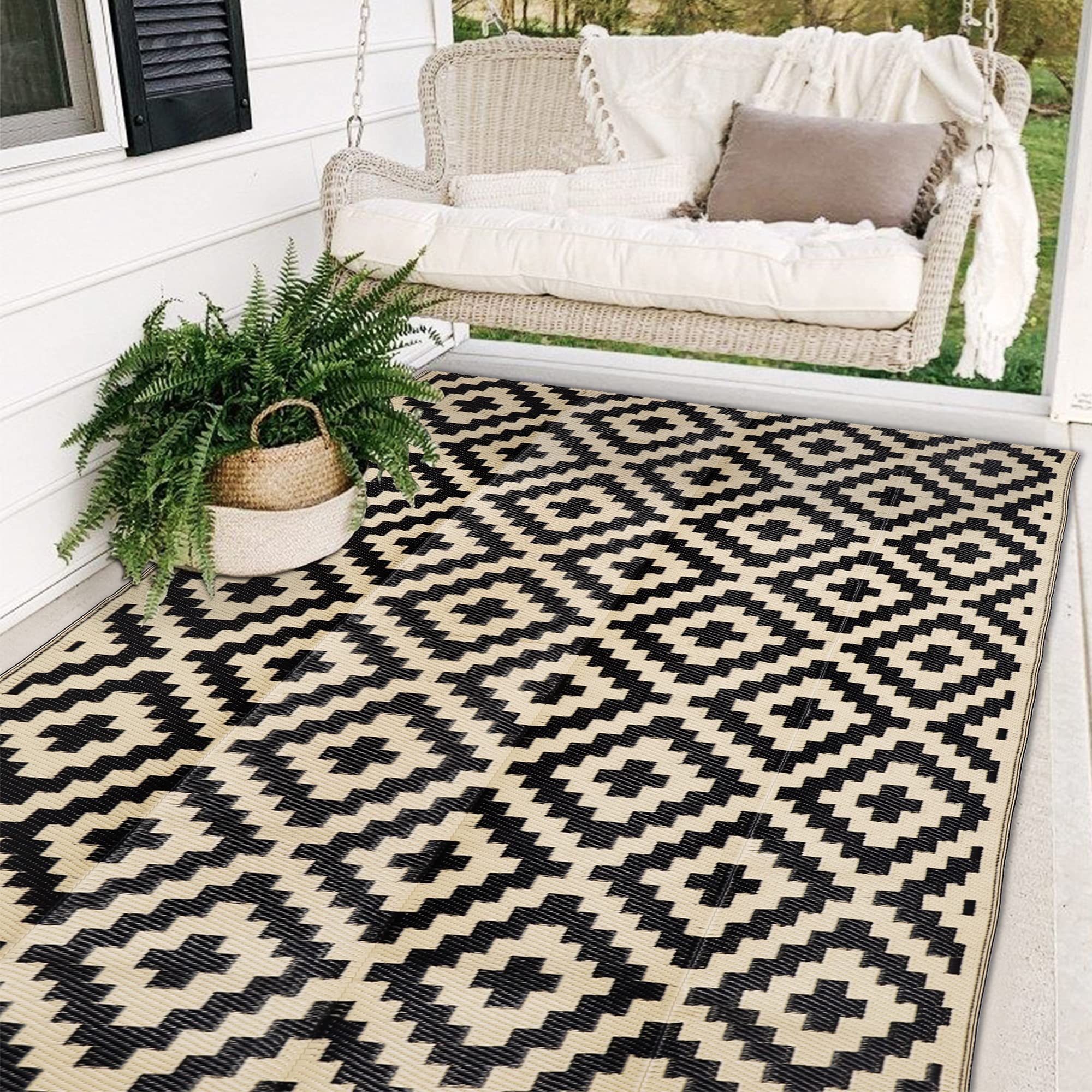 Black and beige reversible 5x8 waterproof outdoor rug on a patio